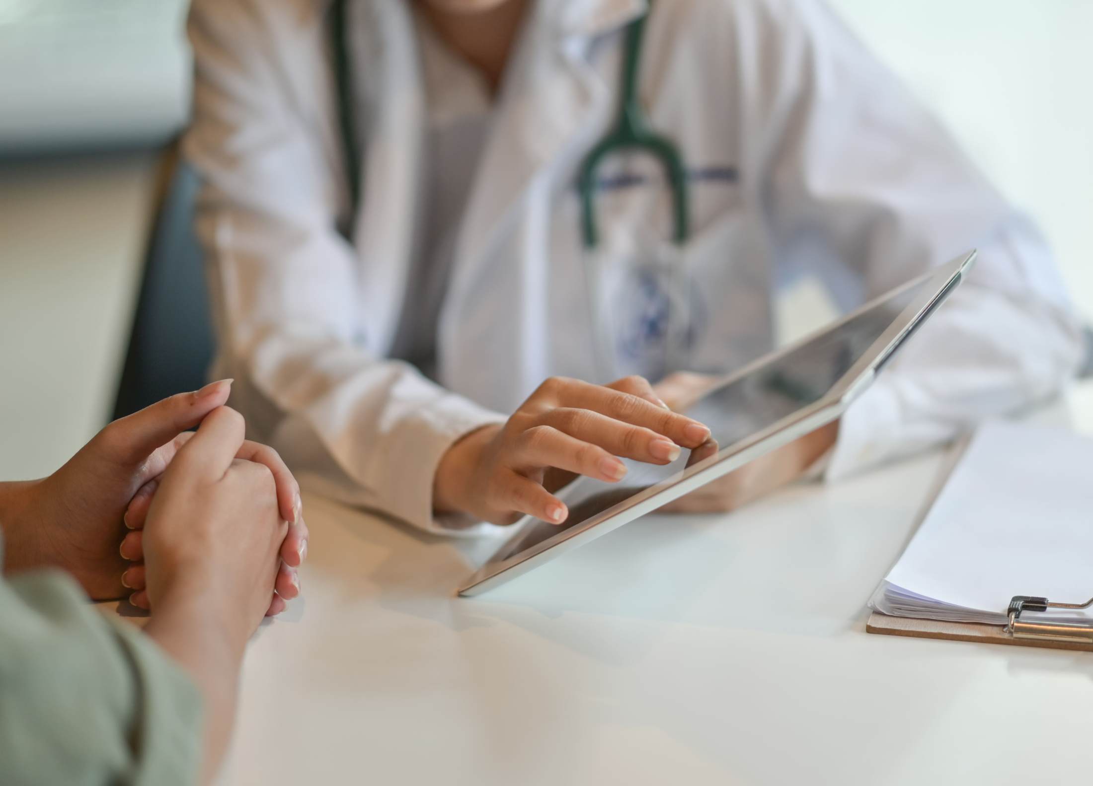 Doctor in white coat using tablet during patient consultation, representing personalized dermatology care and treatment planning.
